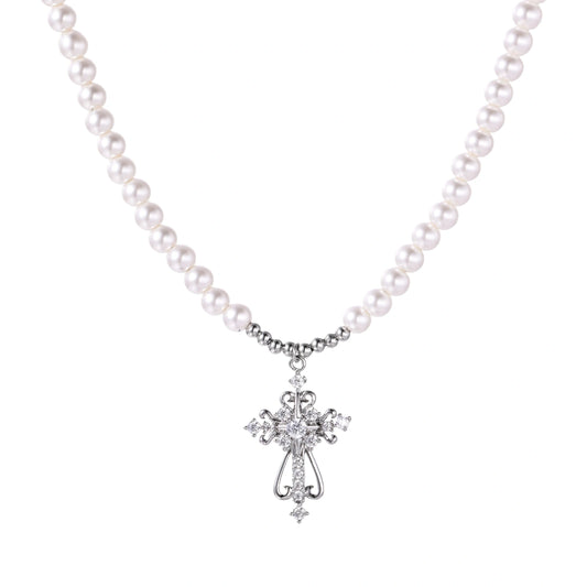 White pearl necklace with ornate silver cross pendant featuring zirconia crystals on cream background.