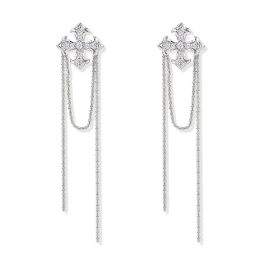 White gold plated baroque cross stud earrings with long cascading zirconia chains on cream background